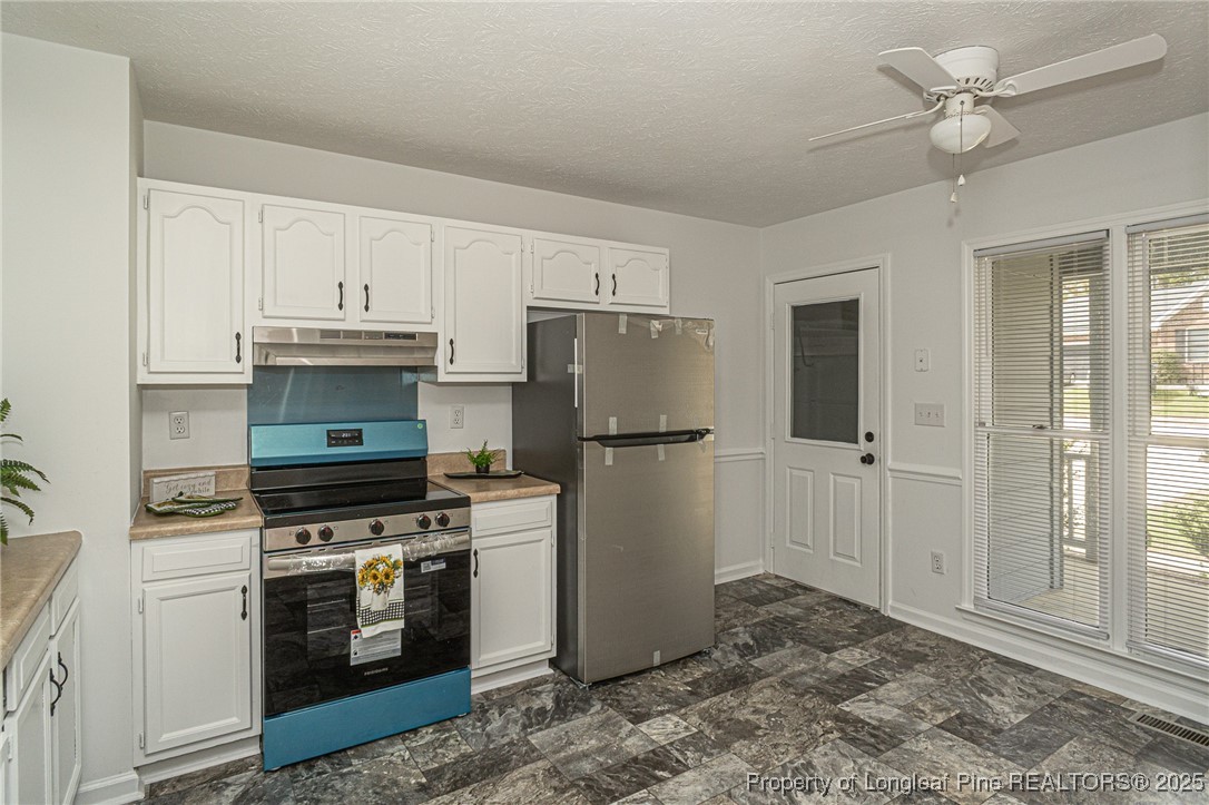 6576 Applewhite Road Fayetteville, NC 28304 - Photo 7 of 35 a kitchen with a refrigerator stove and white cabinets