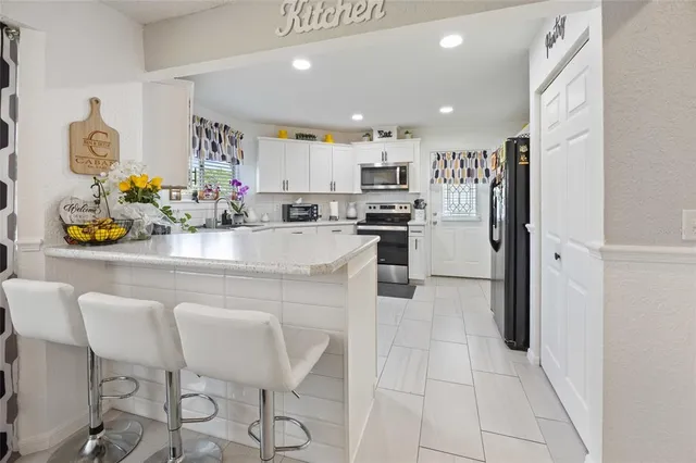 a kitchen with stainless steel appliances kitchen island granite countertop a refrigerator and a sink