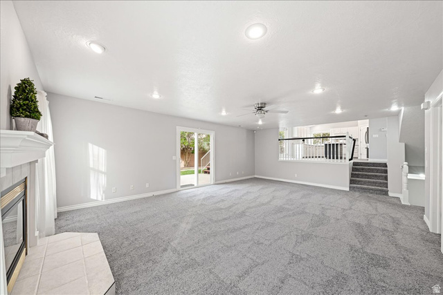 7 Reflection Way St. George, UT 84770 - Photo 19 of 54 Unfurnished living room featuring stairway, light colored carpet, a fireplace, and a ceiling fan