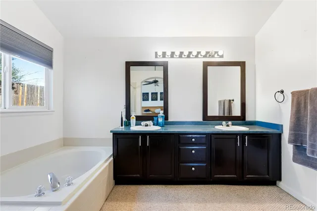a spacious bathroom with a tub sink and mirror