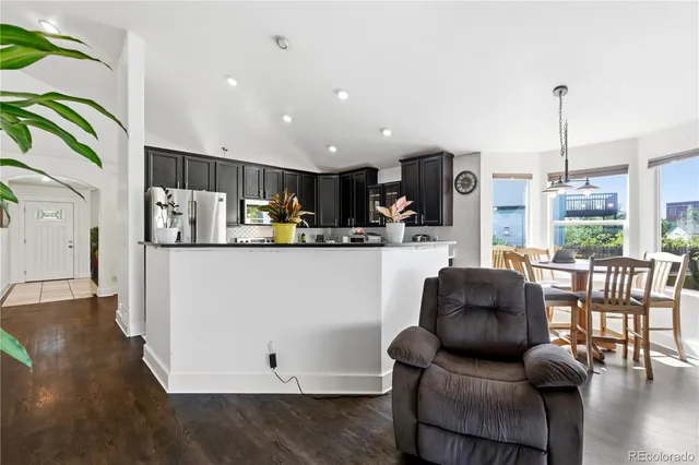 a living room with stainless steel appliances kitchen island granite countertop furniture a refrigerator a sink a stove and a window