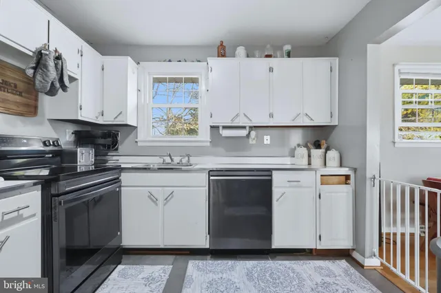 a kitchen with stainless steel appliances granite countertop a stove a sink and white cabinets