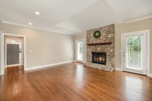 a view of an empty room with wooden floor fireplace and a window
