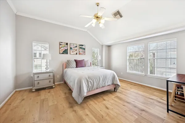 a spacious bedroom with a large bed chandelier and a window