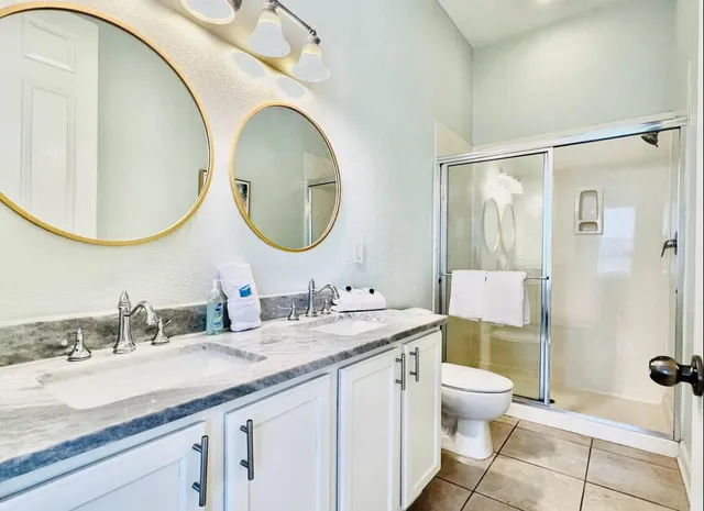a bathroom with a granite countertop toilet a sink and a mirror