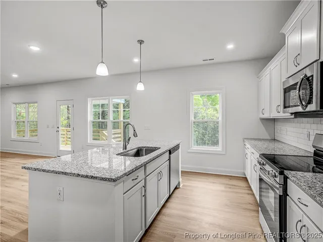 a kitchen with stainless steel appliances granite countertop a stove a sink and a wooden floors