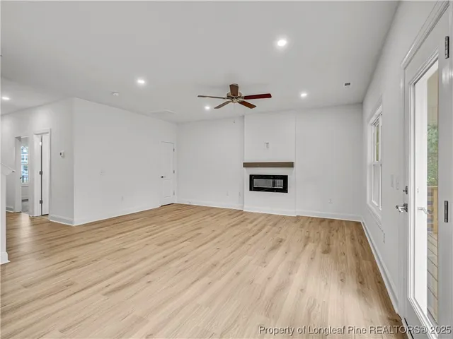 an empty room with wooden floor ceiling fan and windows