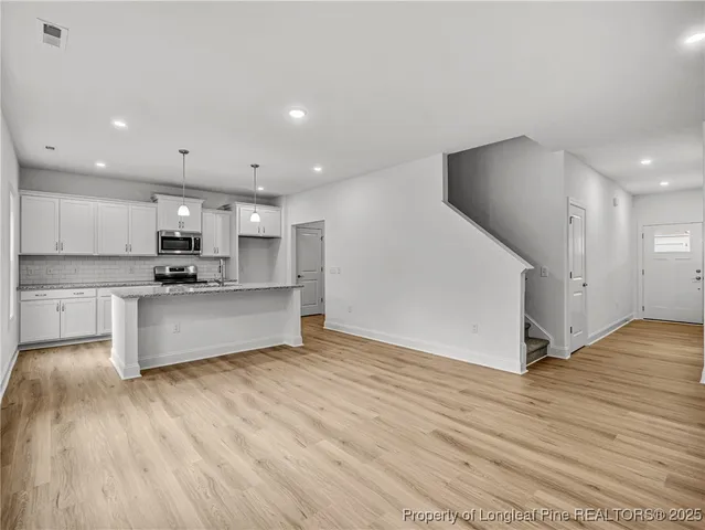 a view of kitchen with kitchen island wooden floor center island and stainless steel appliances