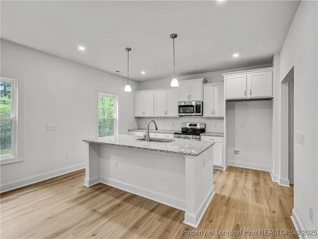 a kitchen with stainless steel appliances granite countertop a sink a stove a refrigerator and island with wooden floor