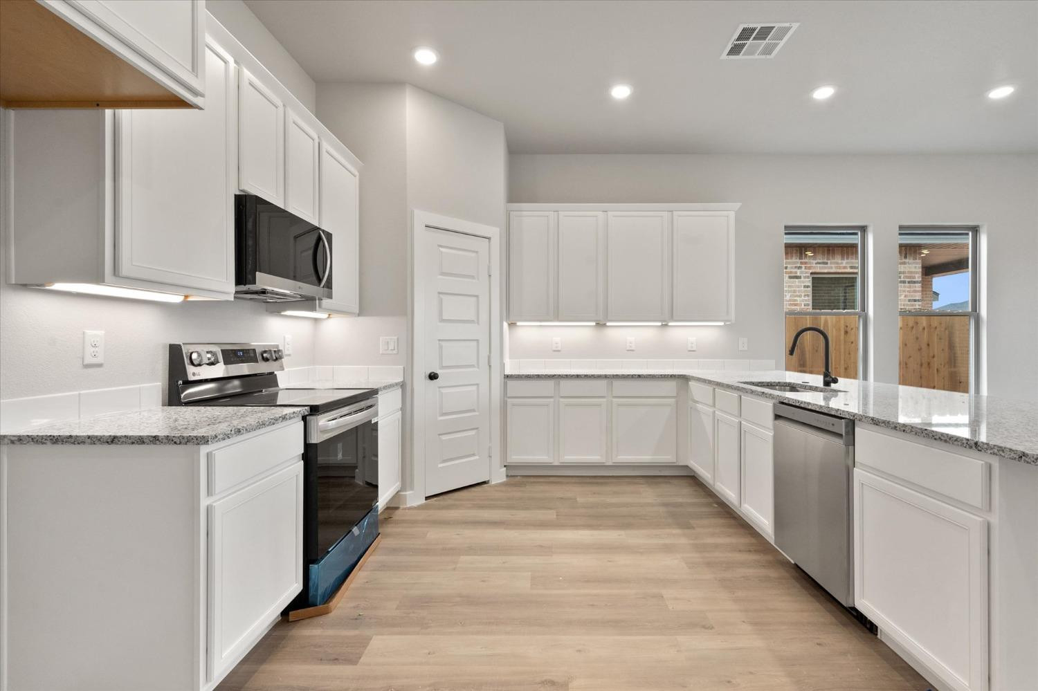 7435 29th Street Lubbock, TX 79407 - Photo 3 of 22 a large white kitchen with stainless steel appliances granite countertop a stove a sink and a microwave