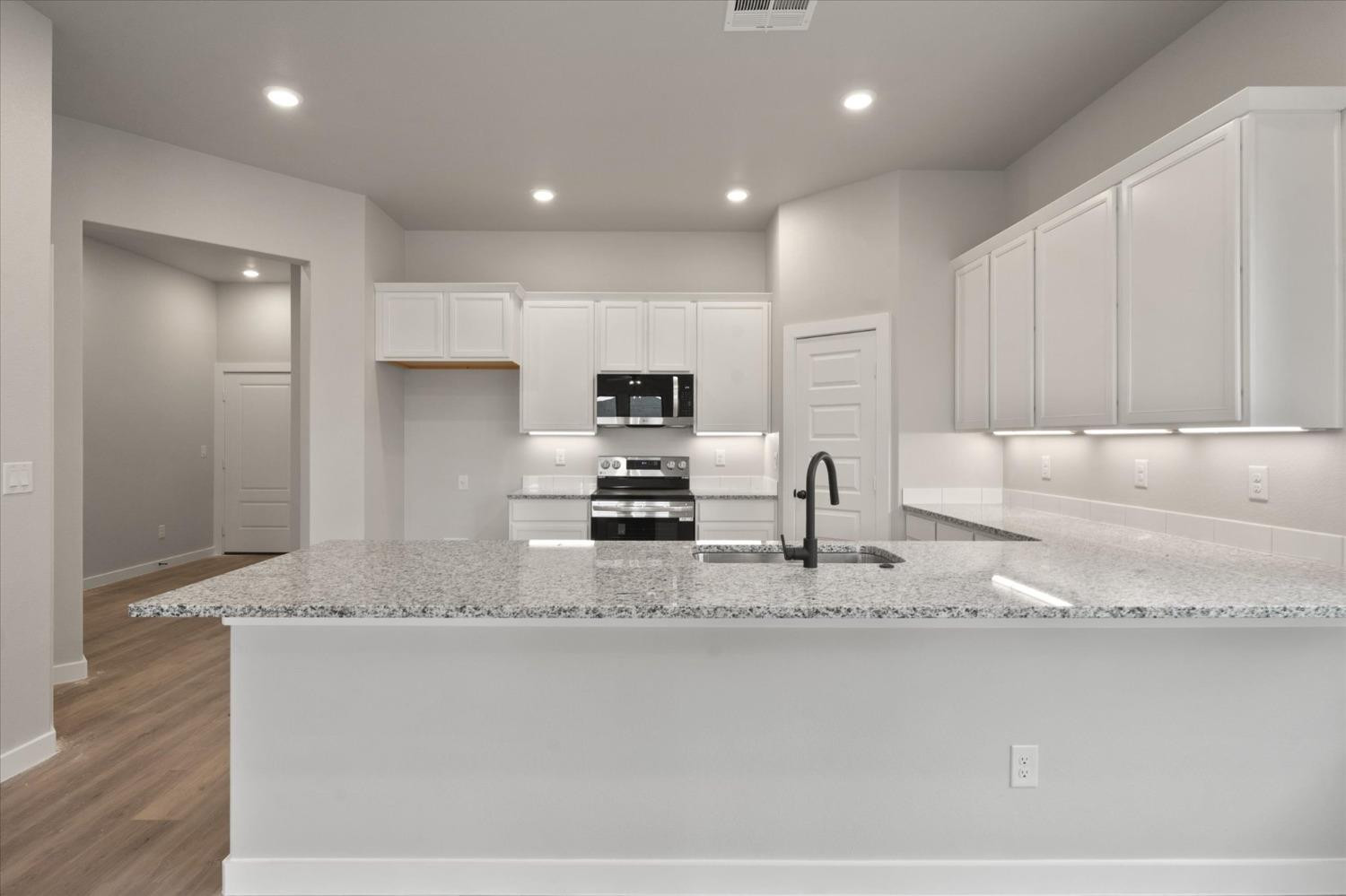 7435 29th Street Lubbock, TX 79407 - Photo 7 of 22 a large kitchen with granite countertop a sink a stove and cabinets