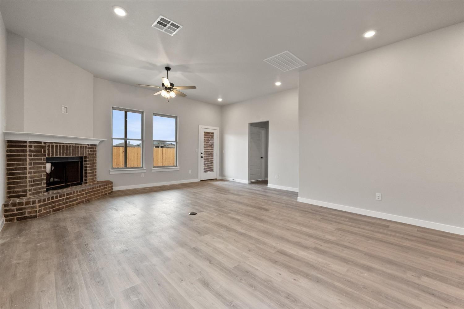 7435 29th Street Lubbock, TX 79407 - Photo 9 of 22 an empty room with wooden floor fireplace and fan
