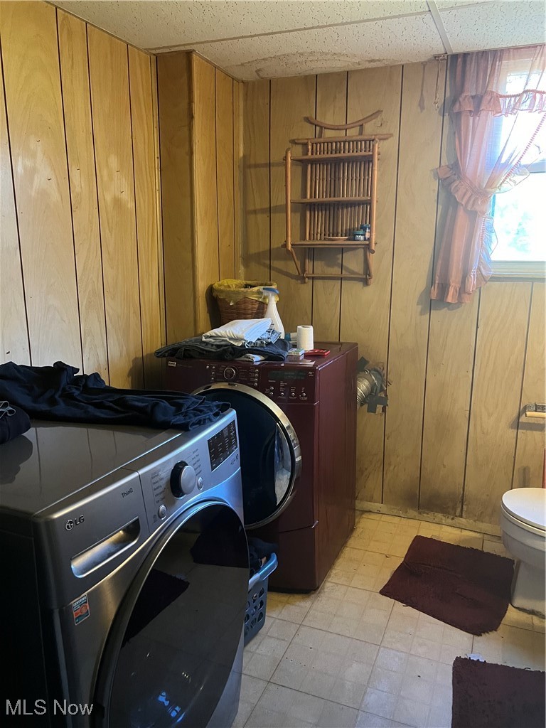 Laundry room featuring separate washer and dryer and wood walls