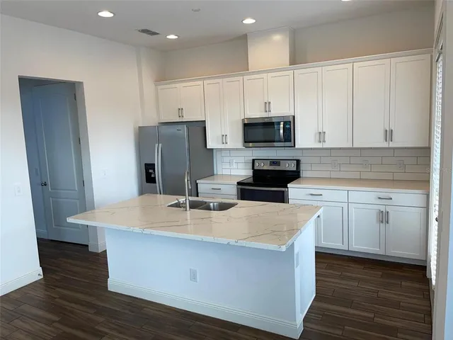 a kitchen with kitchen island white cabinets and stainless steel appliances