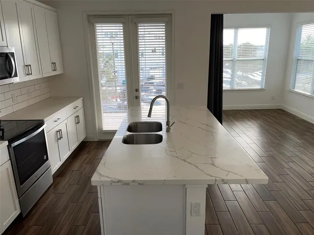 a kitchen with granite countertop a stove a sink and a microwave