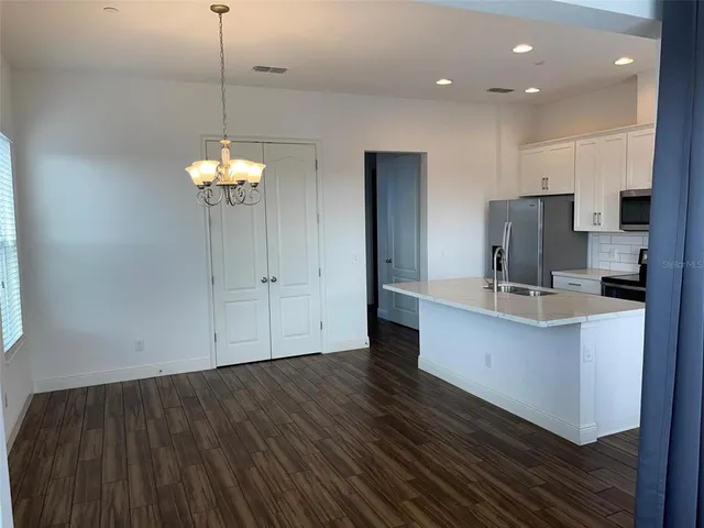a view of kitchen with granite countertop cabinets and refrigerator