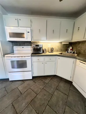 a kitchen with granite countertop white cabinets and refrigerator