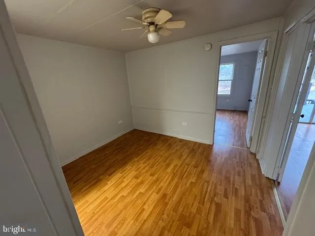 a view of empty room with wooden floor and fan