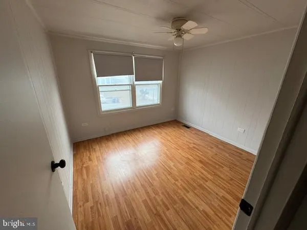 an empty room with wooden floor chandelier fan and windows