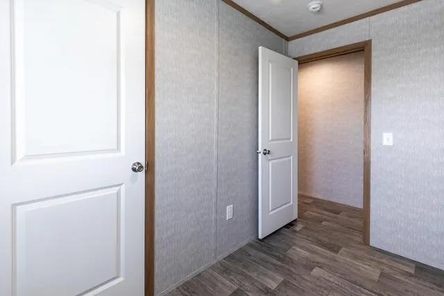 a view of an empty room with wooden floor and closet