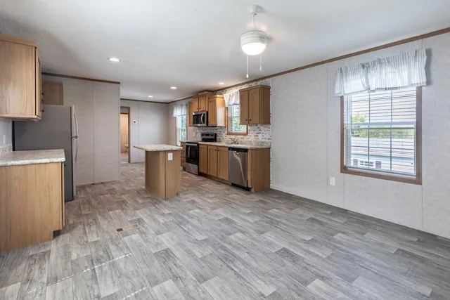 a kitchen with stainless steel appliances granite countertop a refrigerator a sink dishwasher a stove and a refrigerator with wooden floor