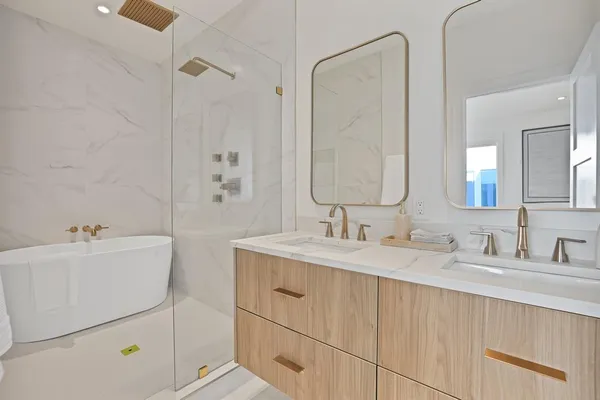 a bathroom with a tub sink double vanity and mirror