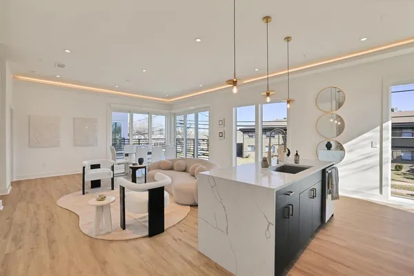 a living room with couches and kitchen view with wooden floor