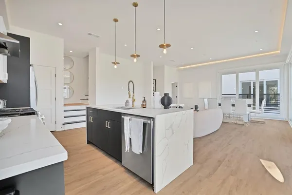 a large white kitchen with a large window a sink and stainless steel appliances