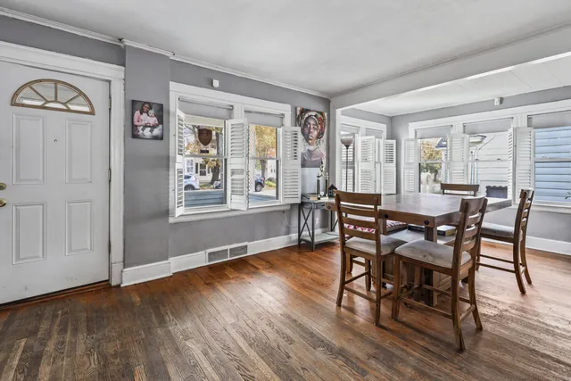 a dining room with wooden floor a chandelier a wooden table and chairs