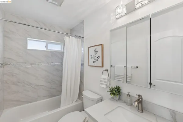a bathroom with a granite countertop bathtub shower sink and toilet