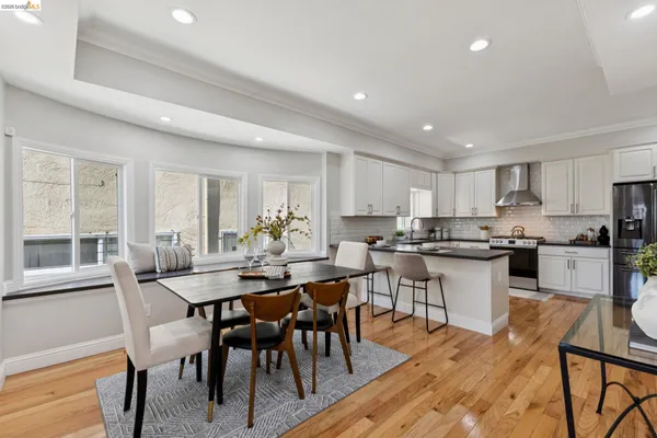 a open dining room with stainless steel appliances kitchen island granite countertop a dining table chairs and a refrigerator