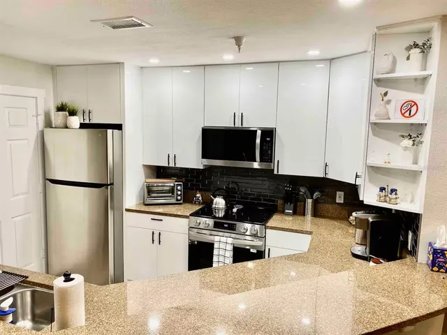 a kitchen with stainless steel appliances kitchen island granite countertop a refrigerator and a stove top oven