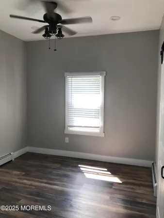 an empty room with wooden floor fan and windows