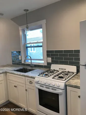a kitchen with granite countertop a sink stove and cabinets