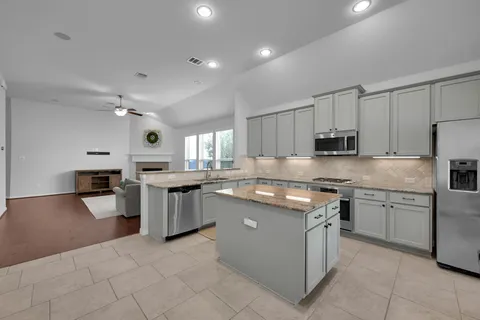 a kitchen with stainless steel appliances granite countertop a stove top oven a sink dishwasher and a refrigerator