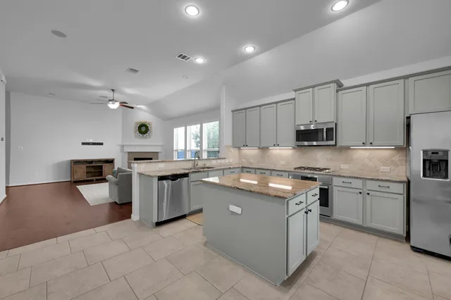 a kitchen with stainless steel appliances granite countertop a stove top oven a sink dishwasher and a refrigerator