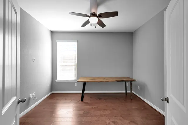 an empty room with a window and a fan