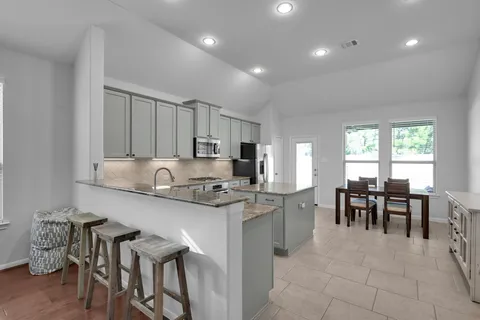 a kitchen with stainless steel appliances granite countertop table chairs and a refrigerator