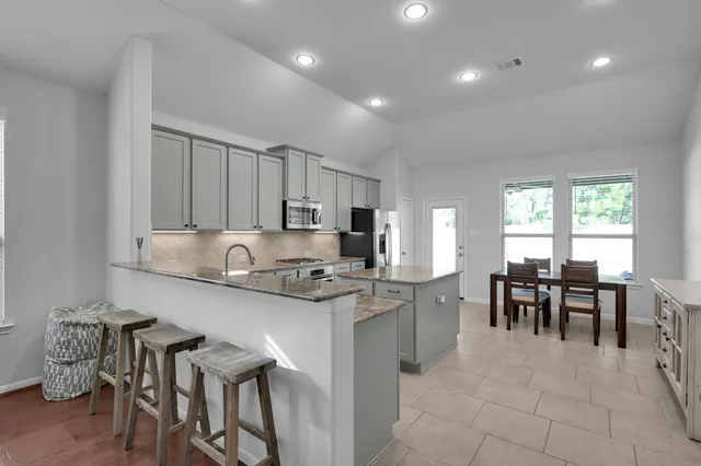 a kitchen with stainless steel appliances granite countertop table chairs and a refrigerator