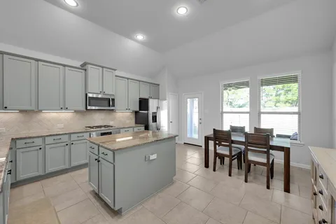 a view of kitchen with granite countertop dining table chairs and white appliances