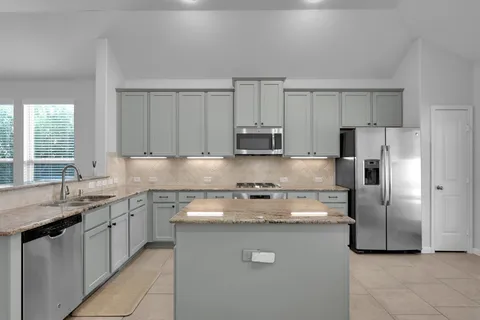 a kitchen with stainless steel appliances granite countertop a sink a stove a refrigerator and a granite counter tops