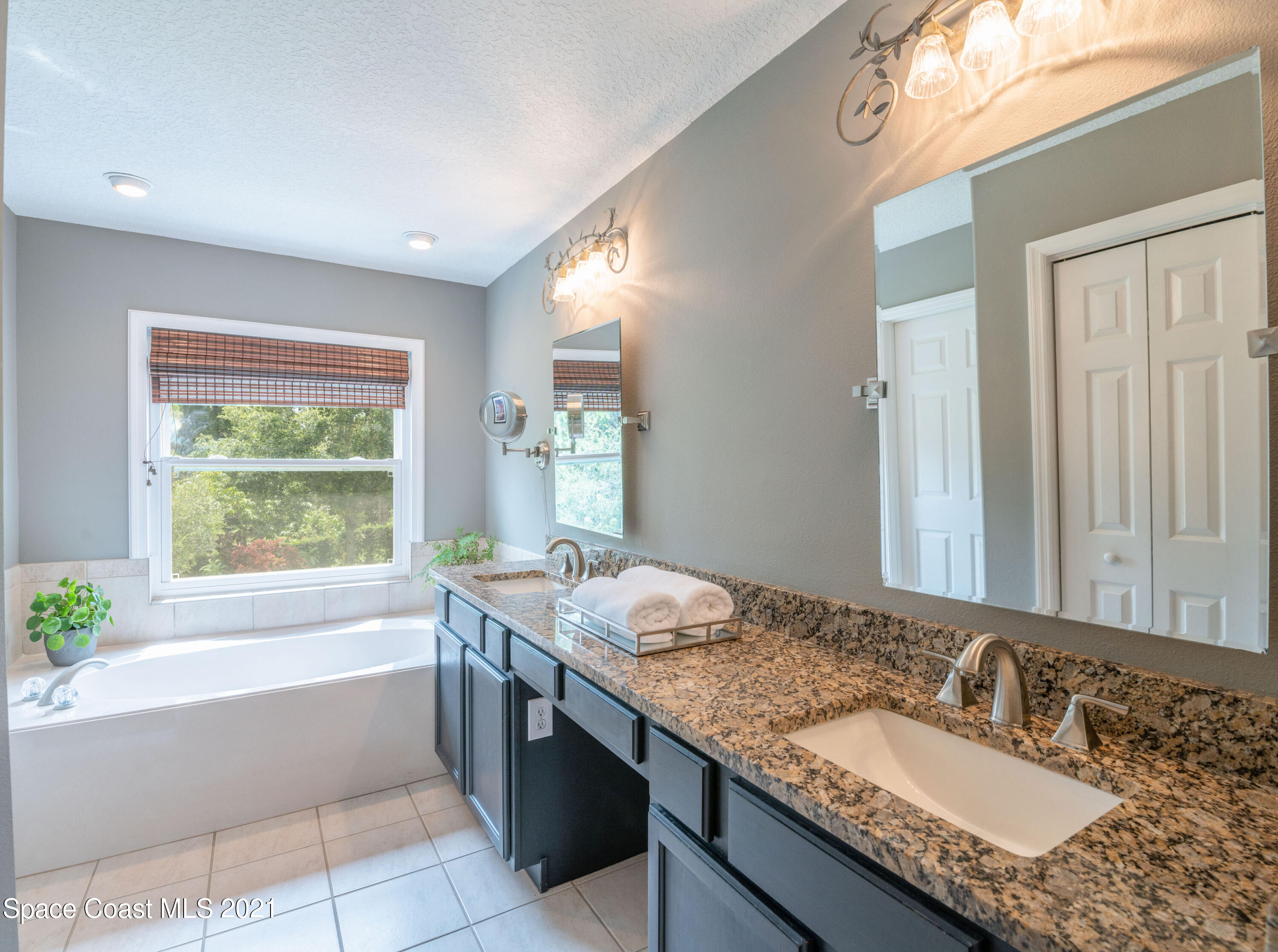 4155 Turtle Mound Road Melbourne, FL 32934 - Photo 22 of 33 a bathroom with a granite countertop bathtub a sink and a window