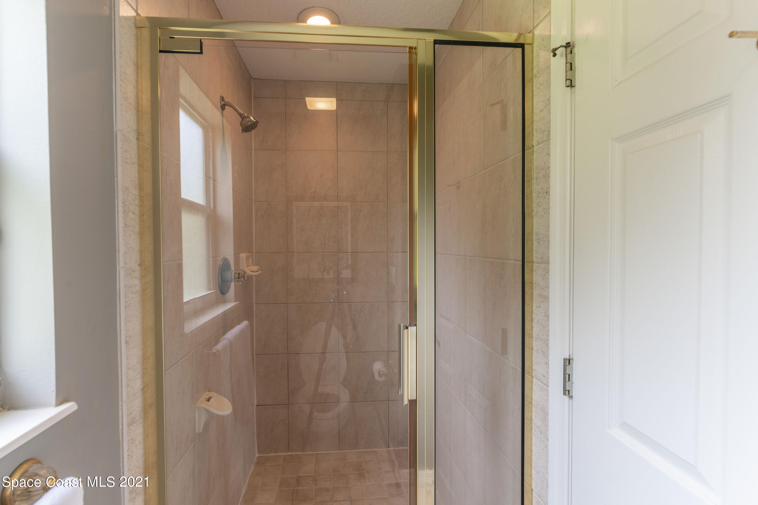 4155 Turtle Mound Road Melbourne, FL 32934 - Photo 23 of 33 a bathroom with a glass shower door