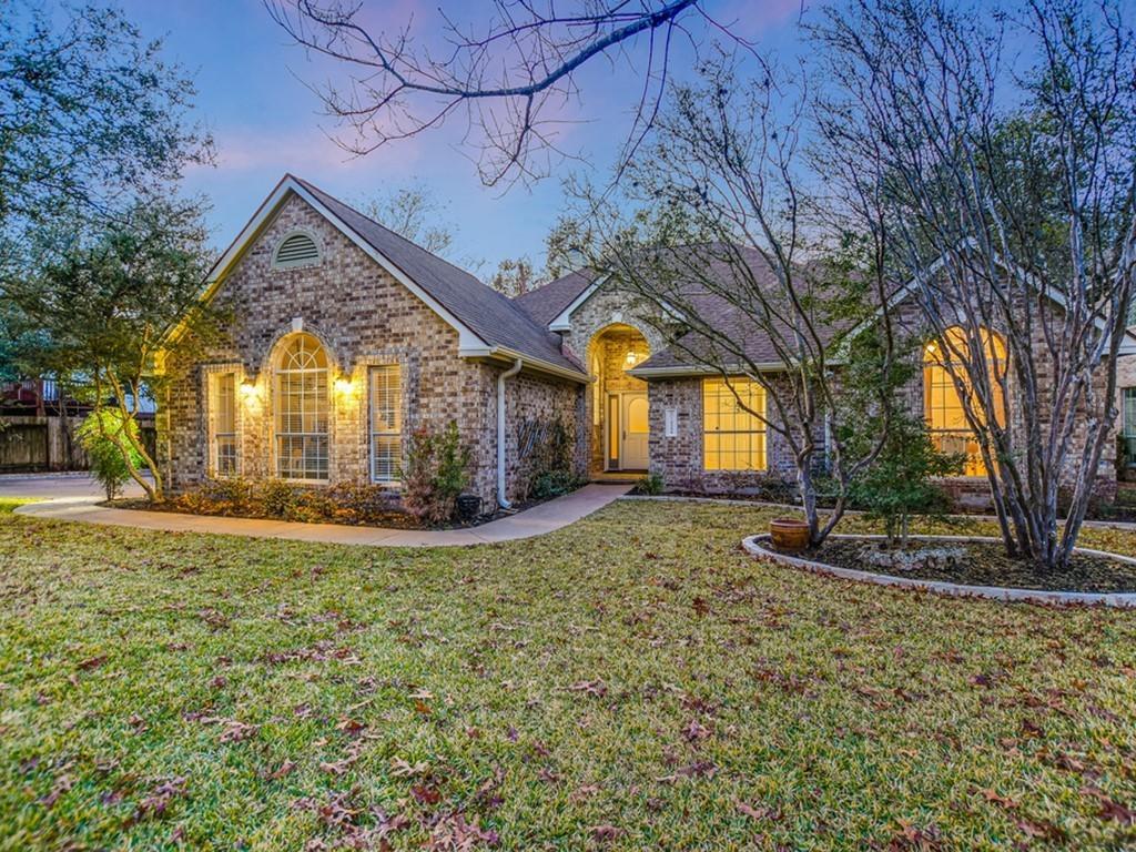 a view of yellow house with a big yard and large tree