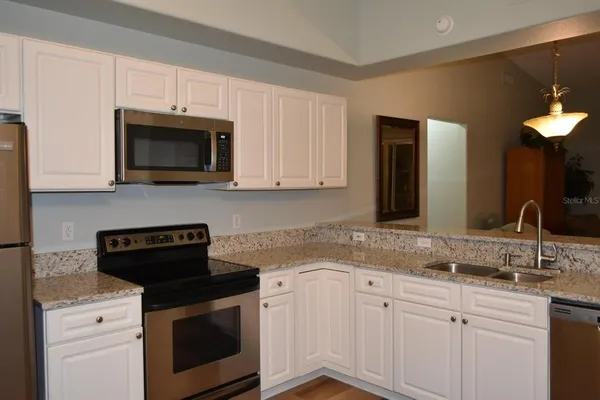 a kitchen with granite countertop a sink dishwasher a stove and a microwave oven with cabinets