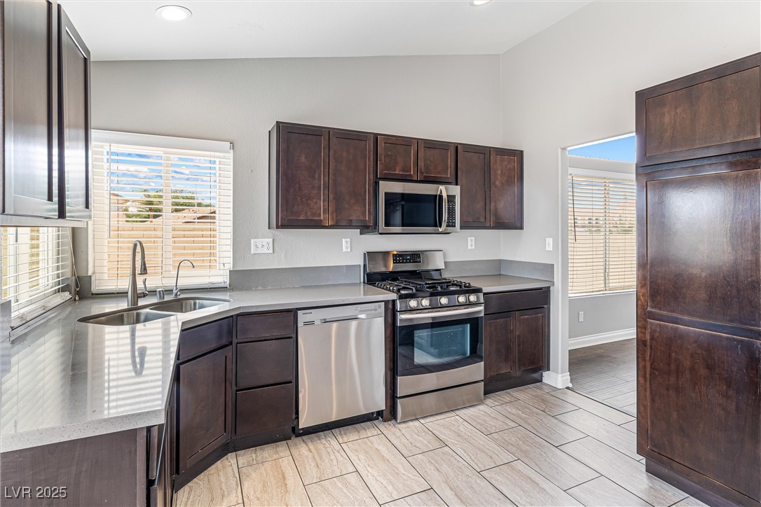 8878 Haviland Road Las Vegas, NV 89123 - Photo 13 of 58 Kitchen with stainless steel appliances, vaulted ceiling, dark brown cabinets, light countertops, and recessed lighting