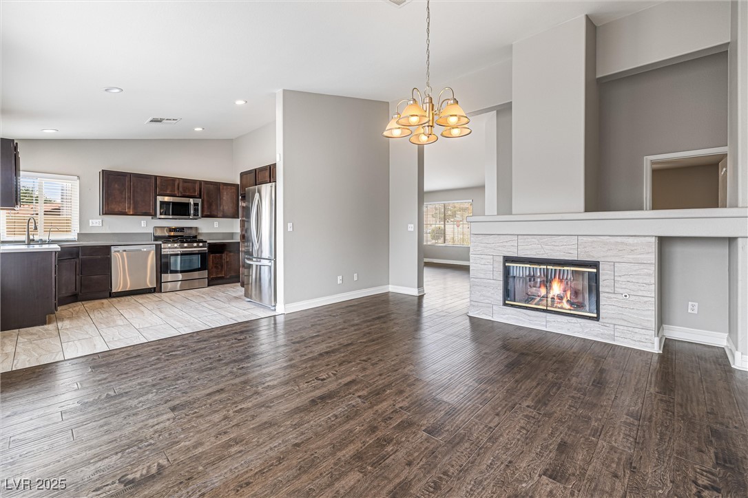 8878 Haviland Road Las Vegas, NV 89123 - Photo 18 of 58 Unfurnished living room with vaulted ceiling, a stone fireplace, light wood finished floors, a chandelier, and recessed lighting