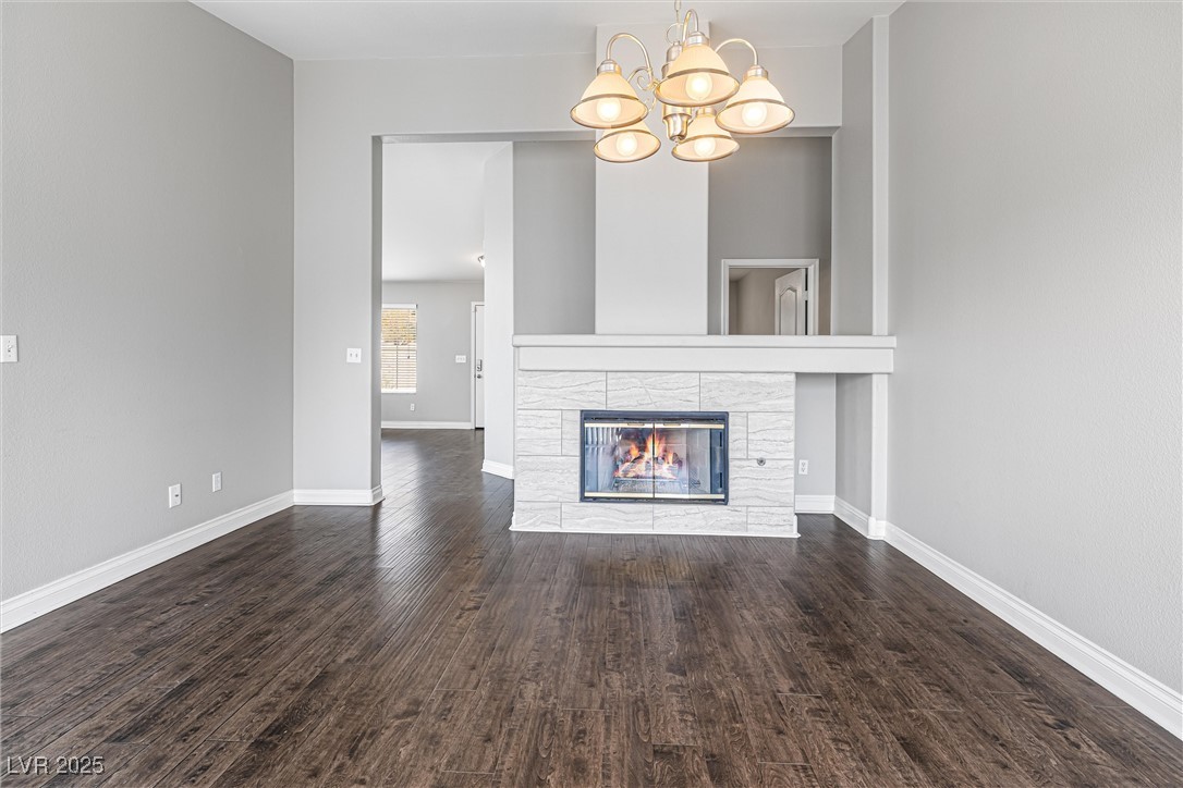 8878 Haviland Road Las Vegas, NV 89123 - Photo 19 of 58 Unfurnished living room featuring a stone fireplace, wood finished floors, and a chandelier