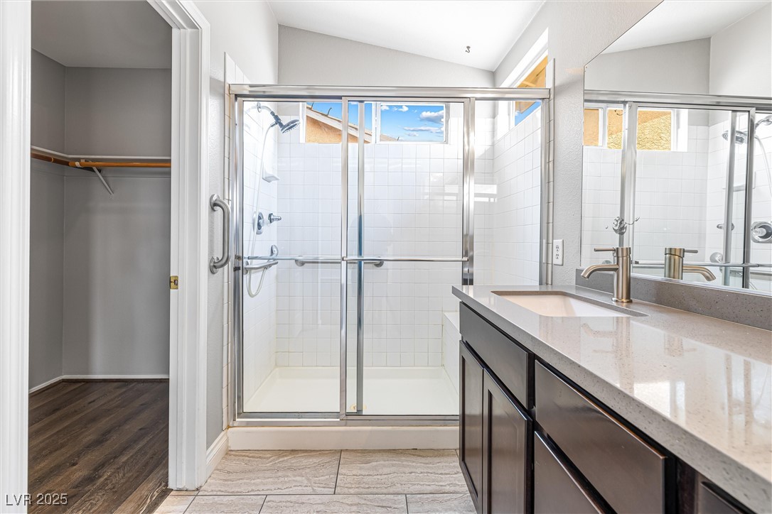 8878 Haviland Road Las Vegas, NV 89123 - Photo 29 of 58 Full bath featuring a walk in closet, a stall shower, vanity, lofted ceiling, and healthy amount of natural light