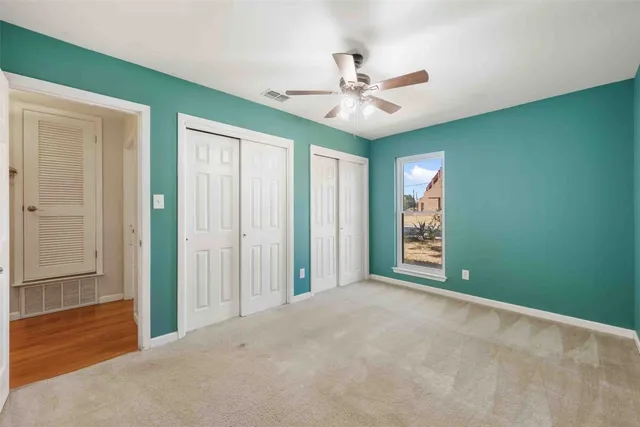 an empty room with windows and fan